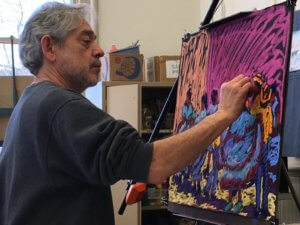 A man draws with pastel on a black piece of paper