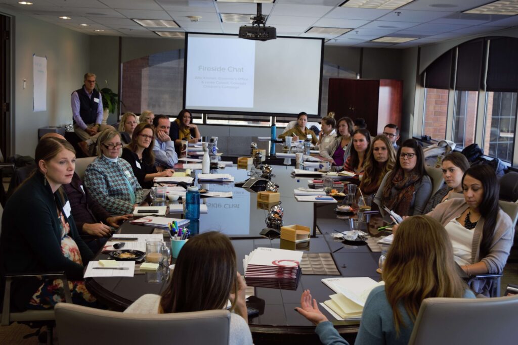 TISPE teachers listen to a presentation in a boardroom