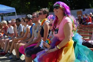 Advocates for LGBTQ rights sit outside listening to a speaker at Boulder Pride