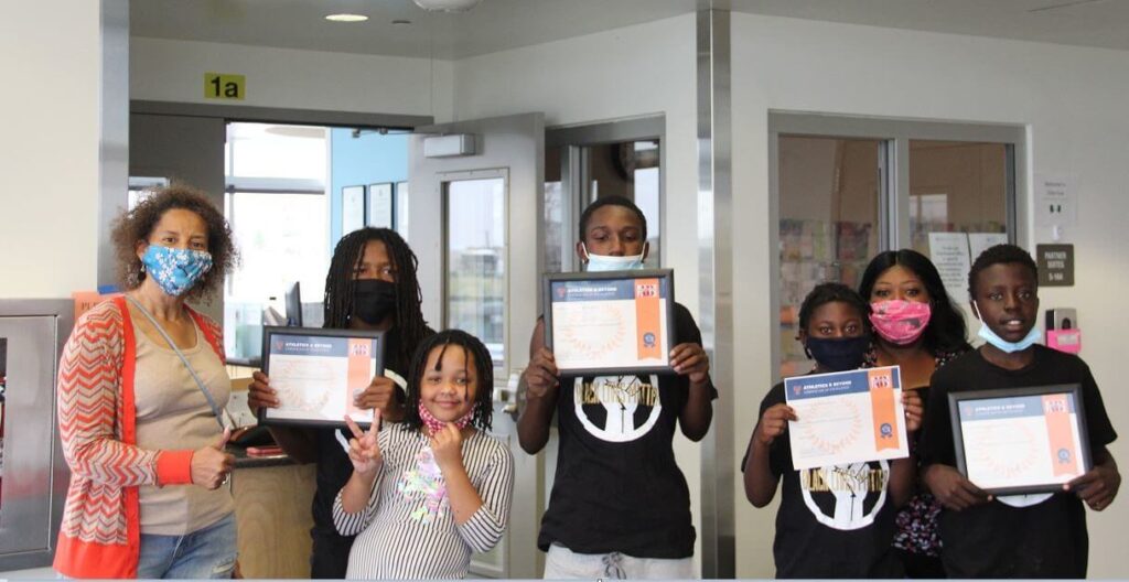 A group of young people of color pose with certificates from Athletics & Beyond
