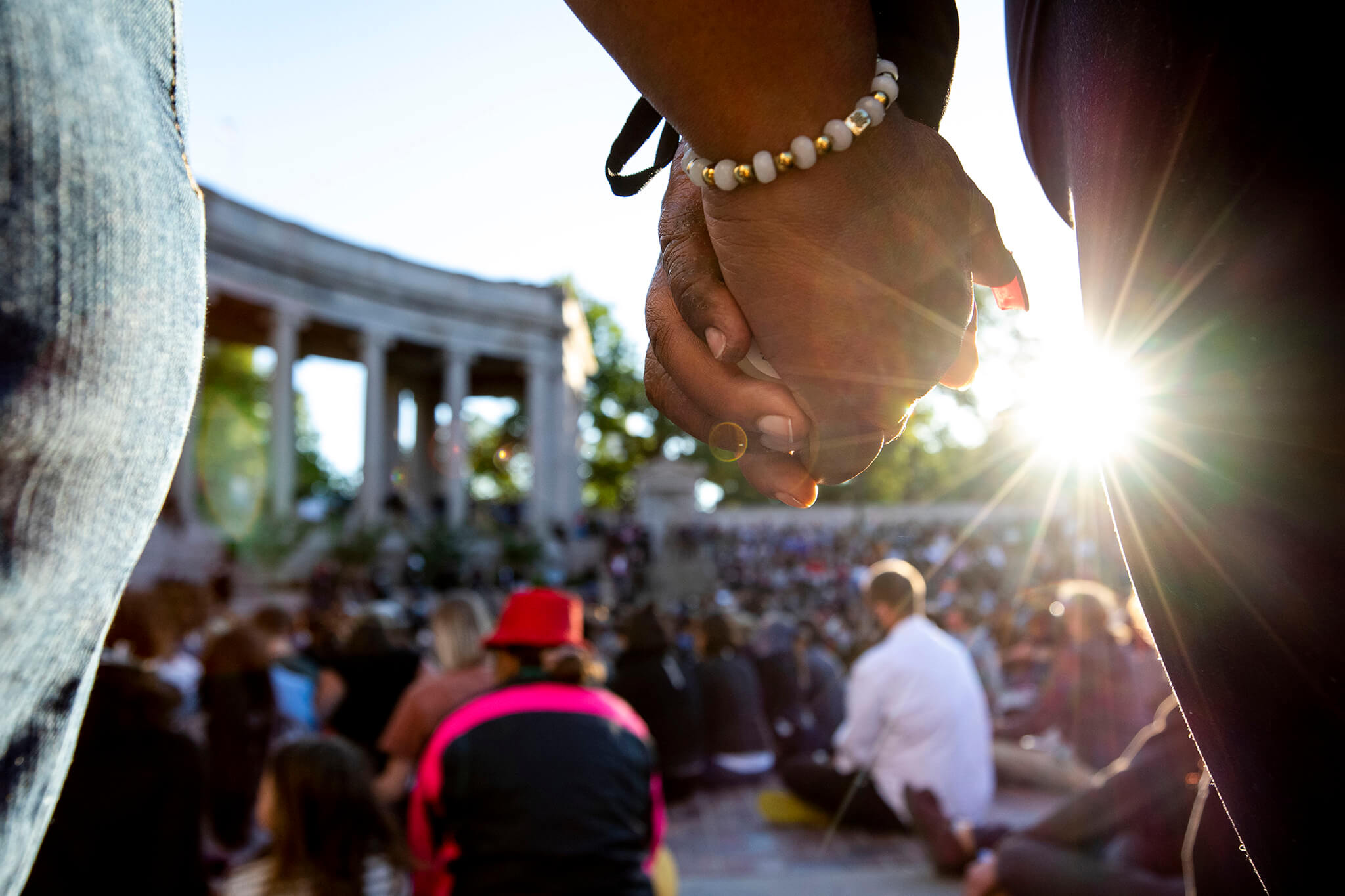 a closeup of two hands holding each other at a vigil for George Floyd at Denver's Civic Center Park