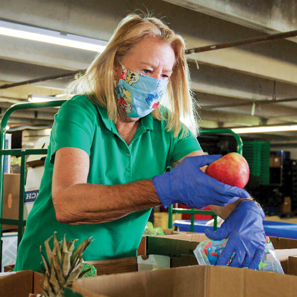 A woman wearing a face covering sorts donations at a food bank