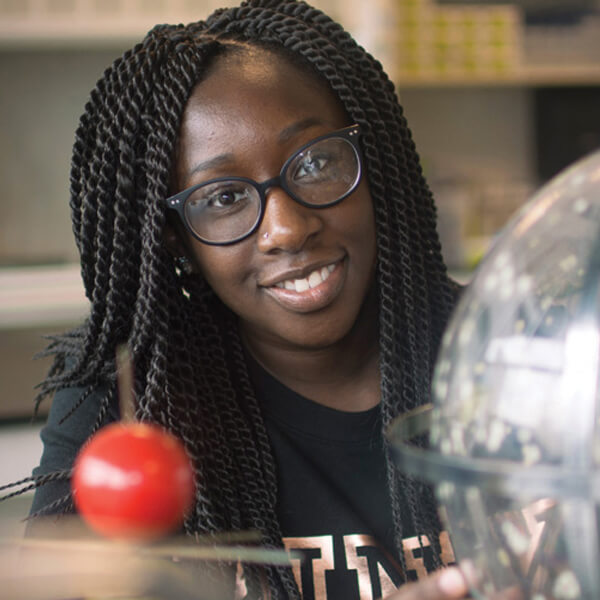 A Black teenager smiling in a science classroom