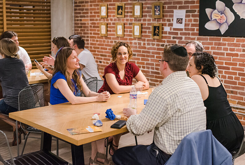 A group of Jewish adults sit at a table for a discussion during an 18Doors event