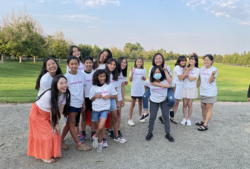 A group of Asian teen girls hanging out in a park wearing shirts that say "Asian Girls Ignite"