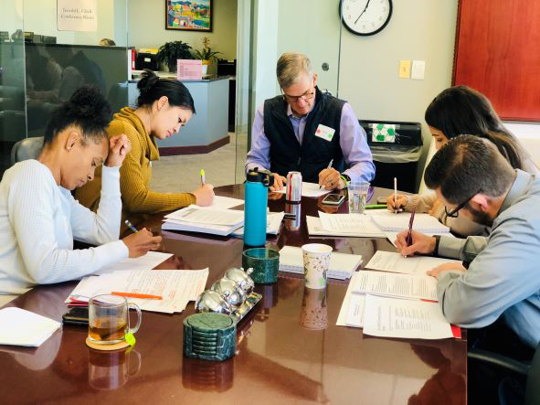 A group of people reviews printed materials at a table