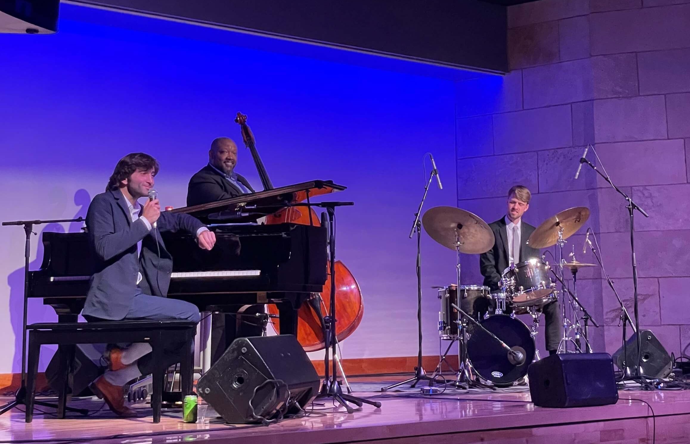 A three-piece jazz band plays music on a stage