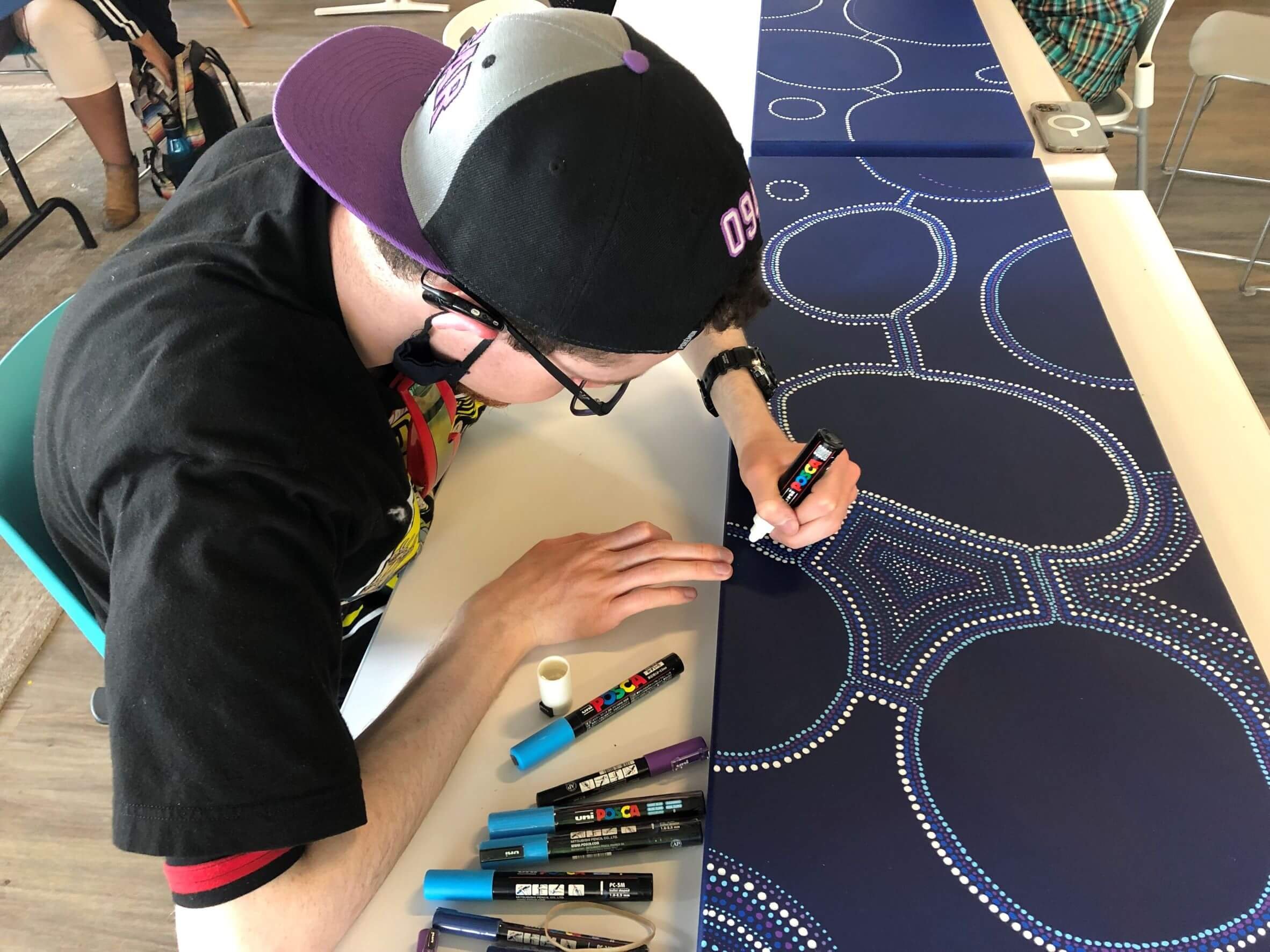 An artist at Access Gallery works on a piece using markers on paper