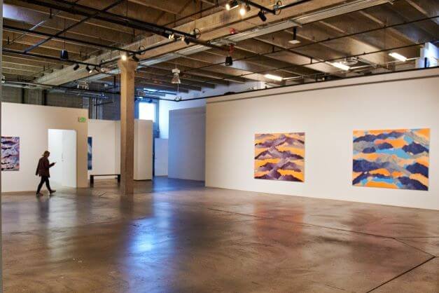 A view of a gallery with colorful abstract expressionist paintings